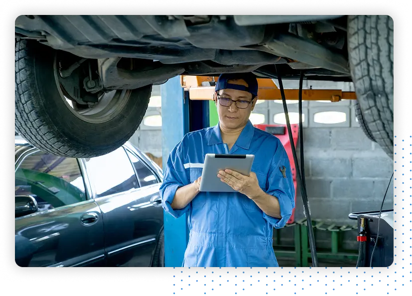 Mechanic under a car taking notes on a tablet