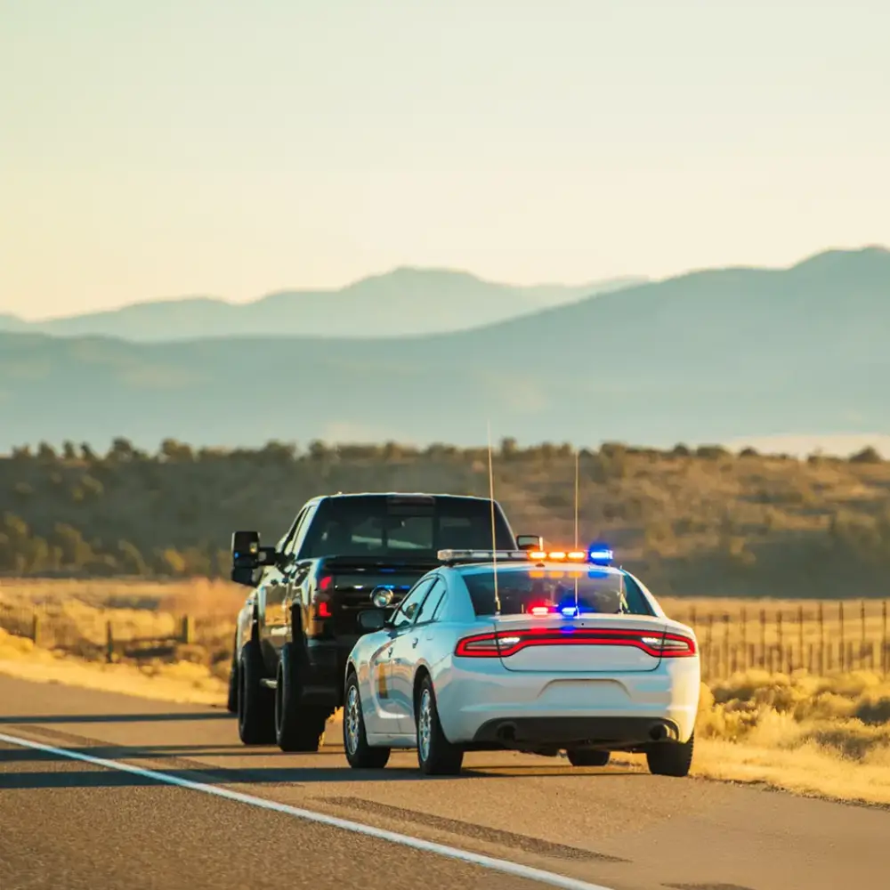 White police car pulling over a black pickup truck